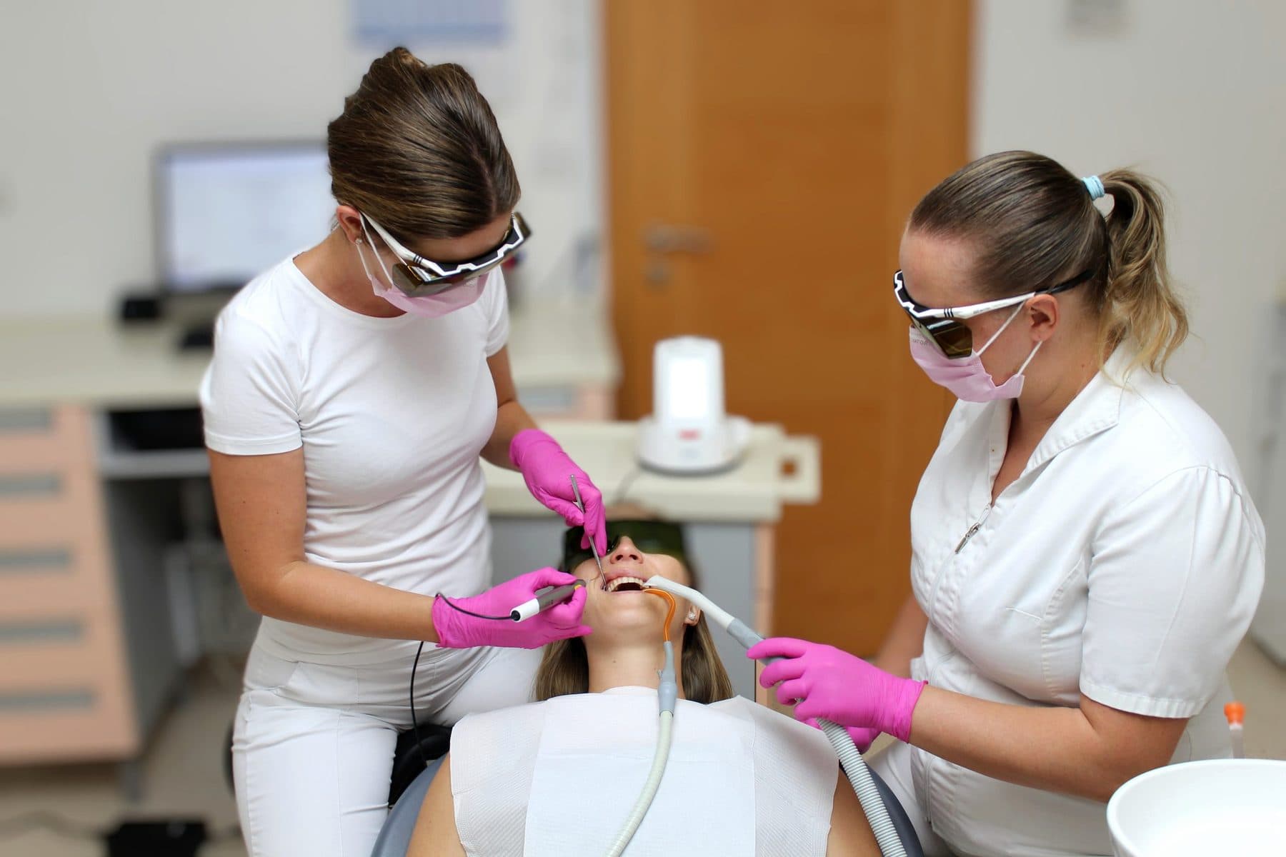 Zwei Mitarbeiterinnen der Praxis Pintarić Dental bei einer Laserbehandlung, beide mit Schutzbrillen für die Laserarbeit