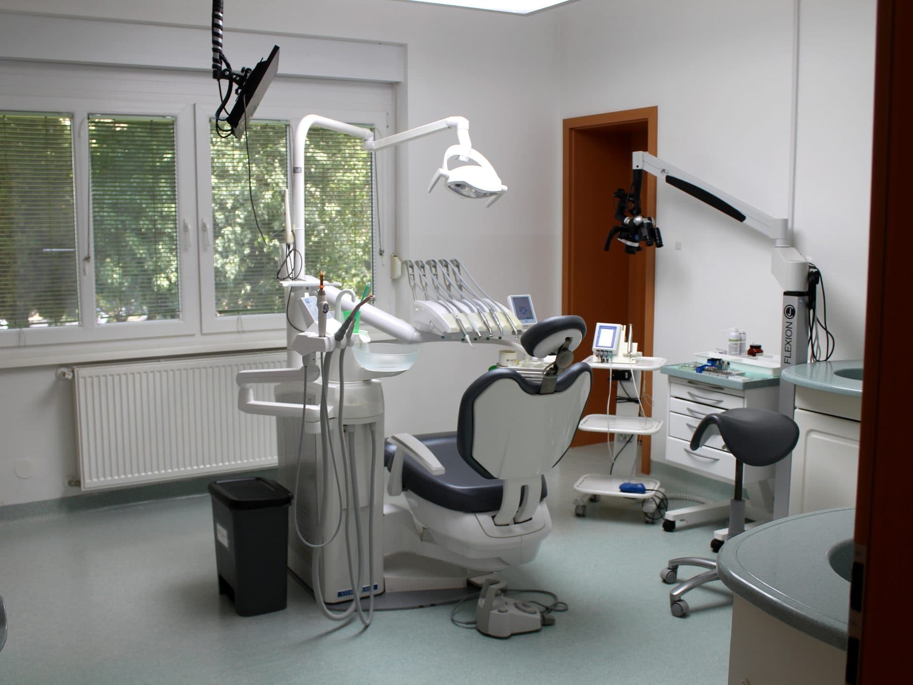 Der grüne Behandlungsraum von Pintarić Dental in Ptuj mit Behandlungsstuhl